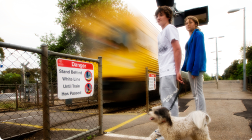 Pedestrians stopped at a level crossing with train passing by